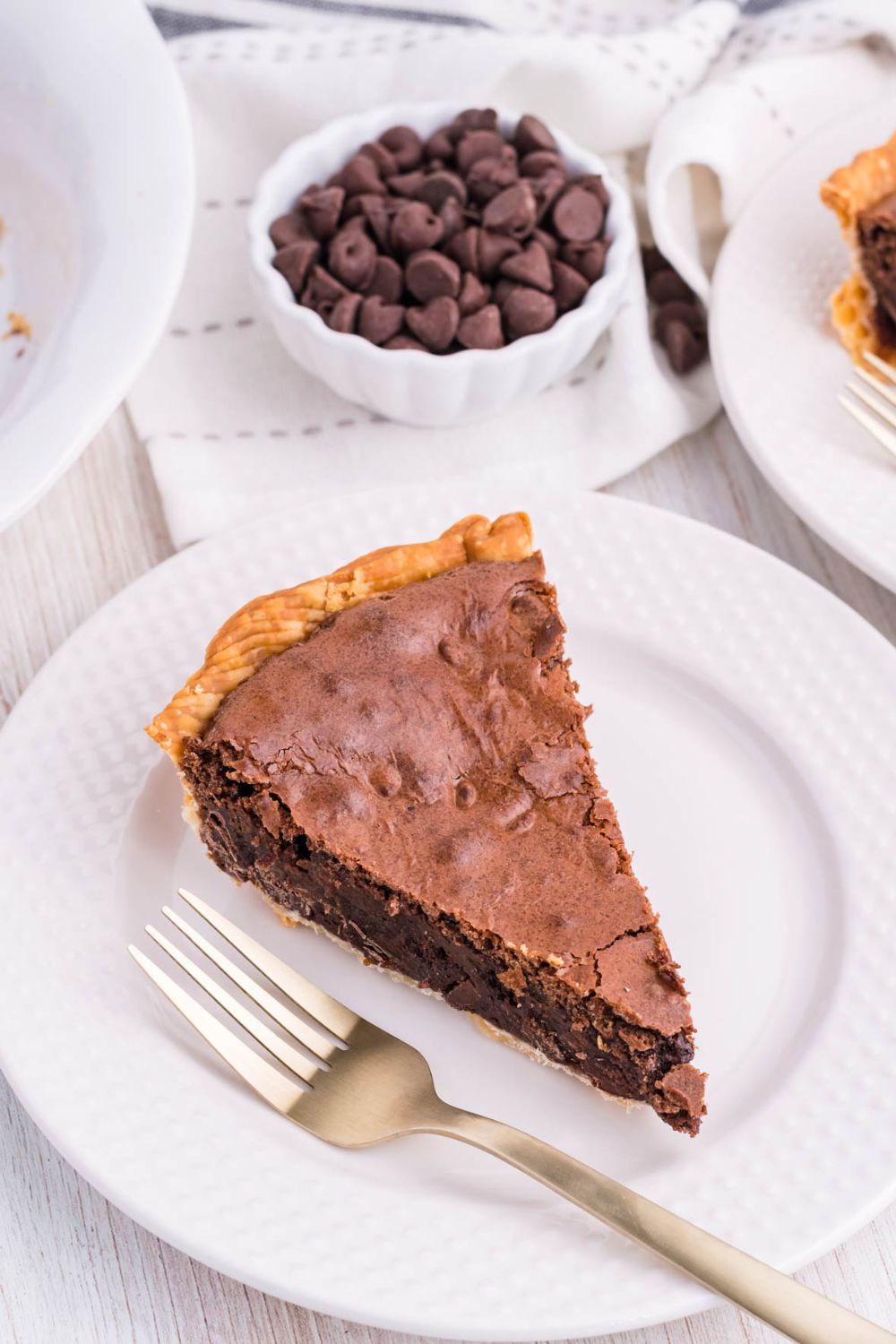 chocolate pie on plate with bowl of chocolate chips behind it