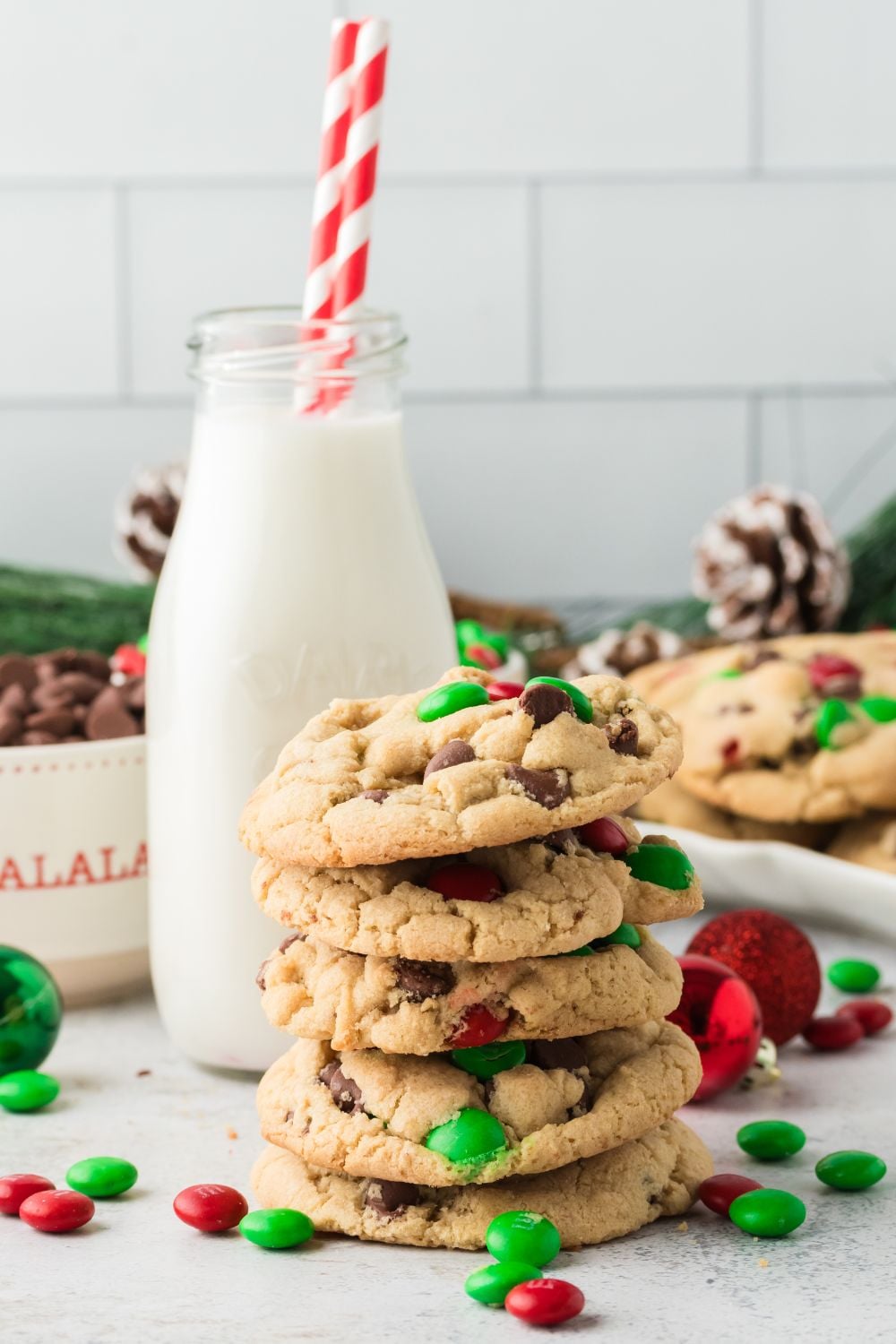 Christmas M&M Cookies on table with milk in jug behind it