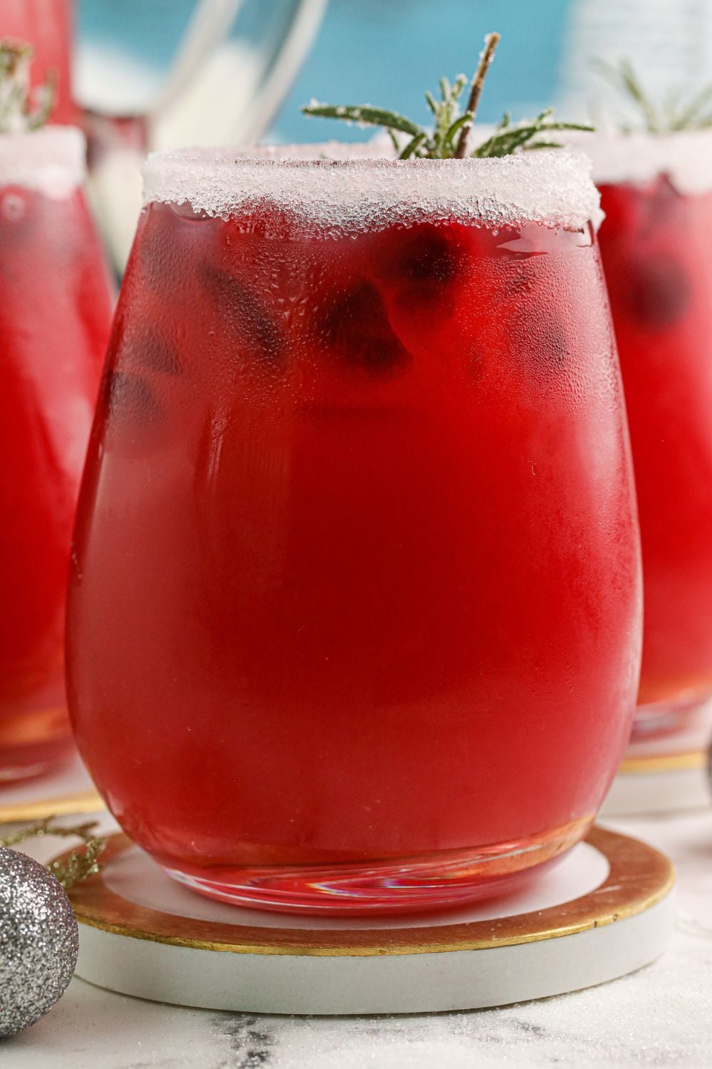 side view of a glass full of a cranberry cocktail on a coaster on table