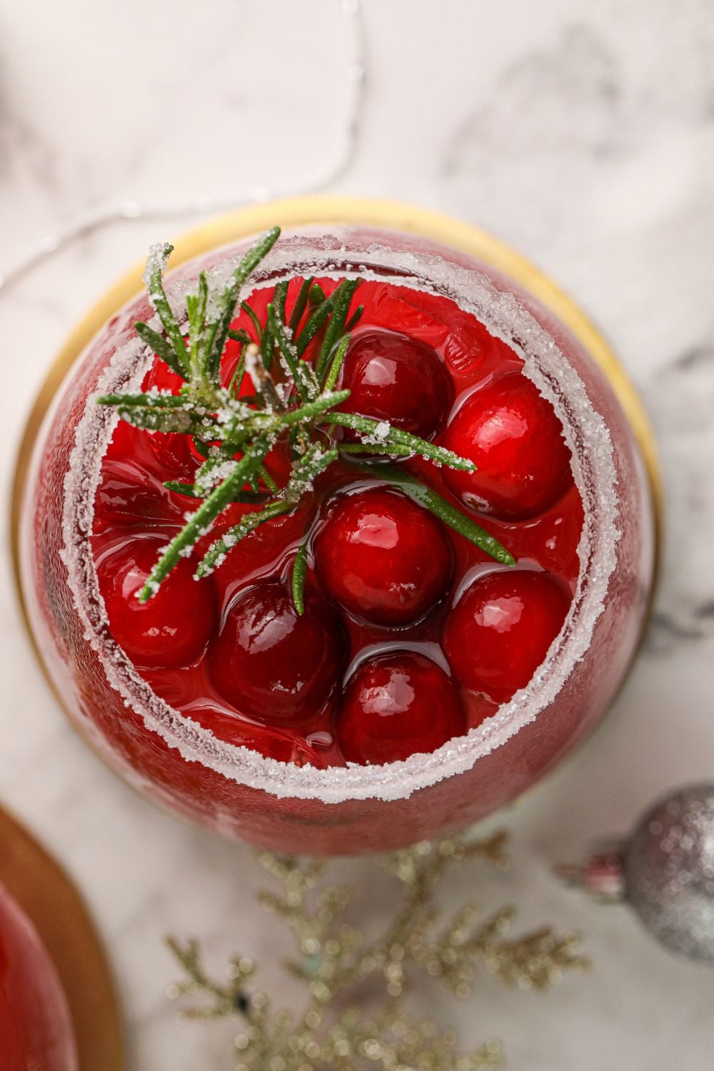 overhead shot of cranberry margarita in glass on marble counter 