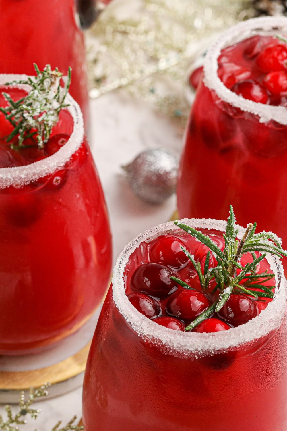 orange cranberry cocktails in glasses on table with christmas decorations around the glasses 