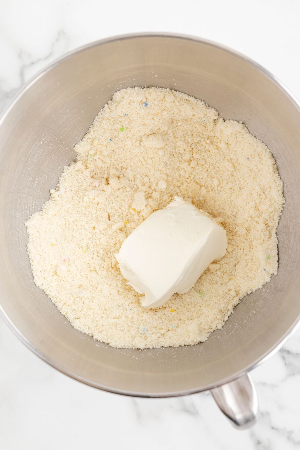 crushed cookies in a bowl with a block of cream cheese on top