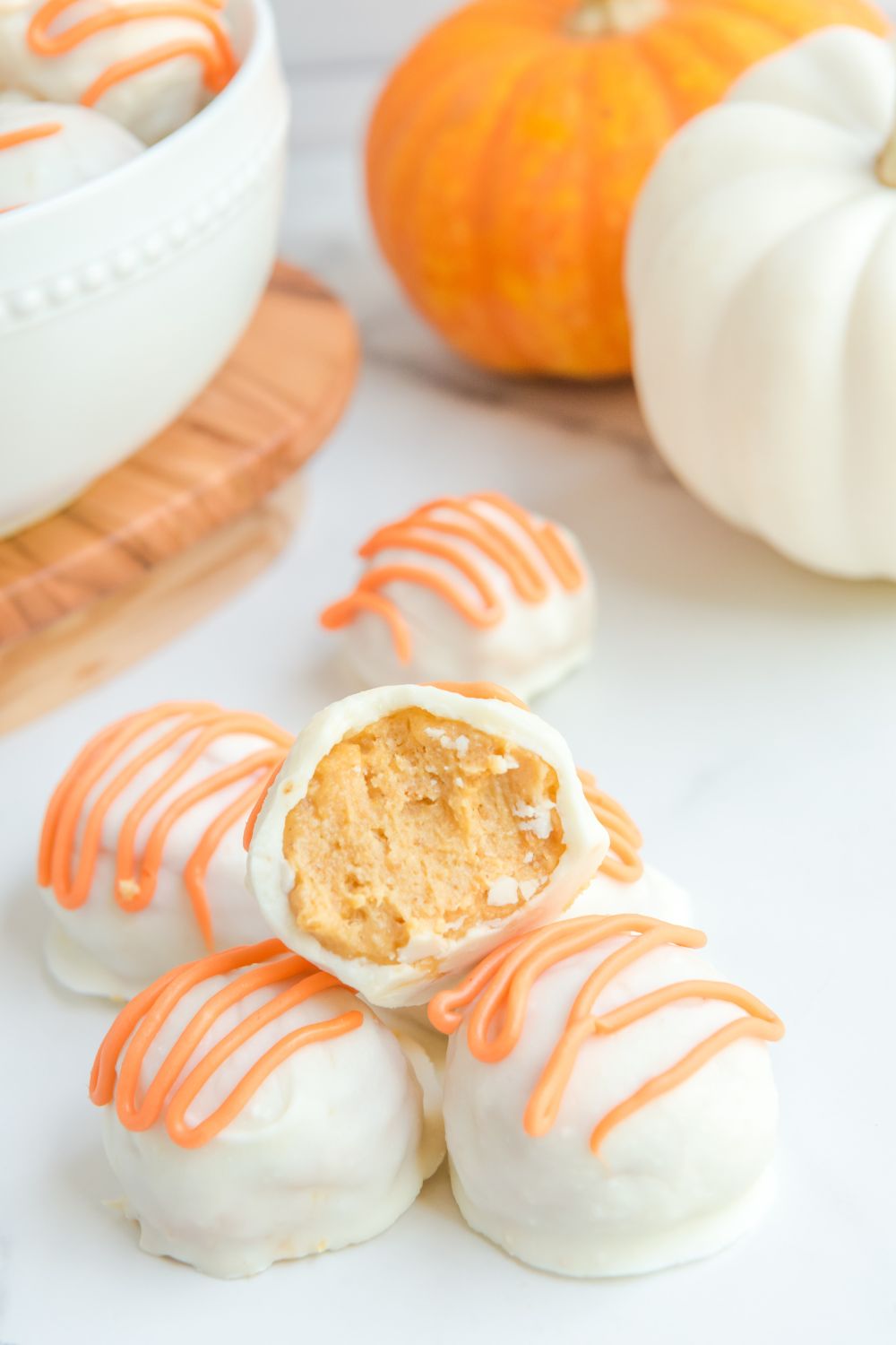 White Chocolate Pumpkin Truffles on table with a bite taken out of one of them 