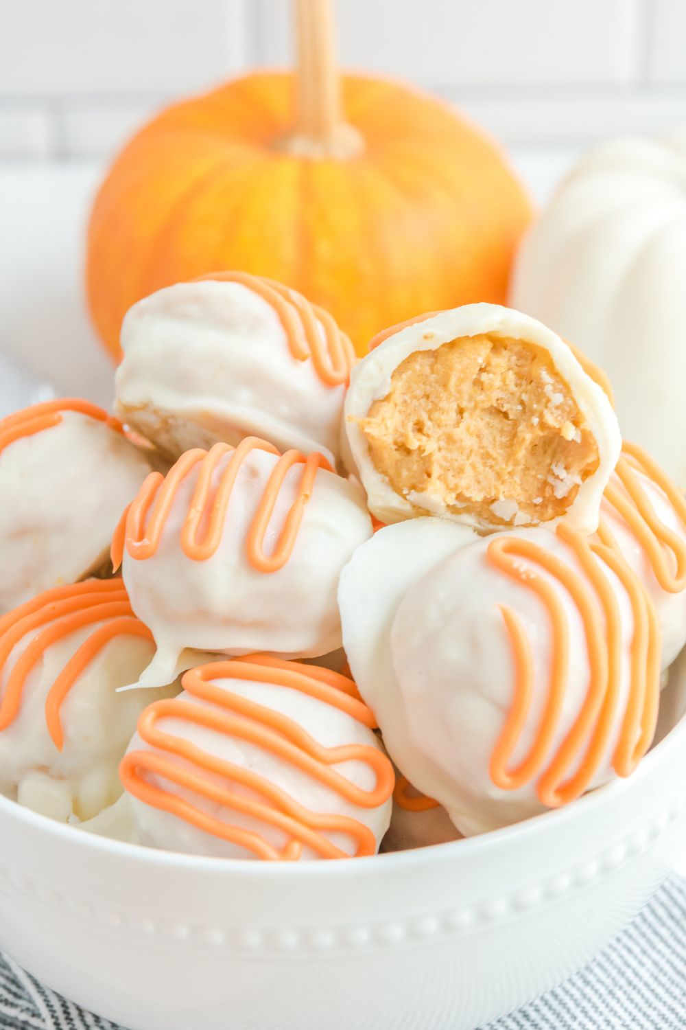 White Chocolate Pumpkin bites in a bowl with one bit in half 