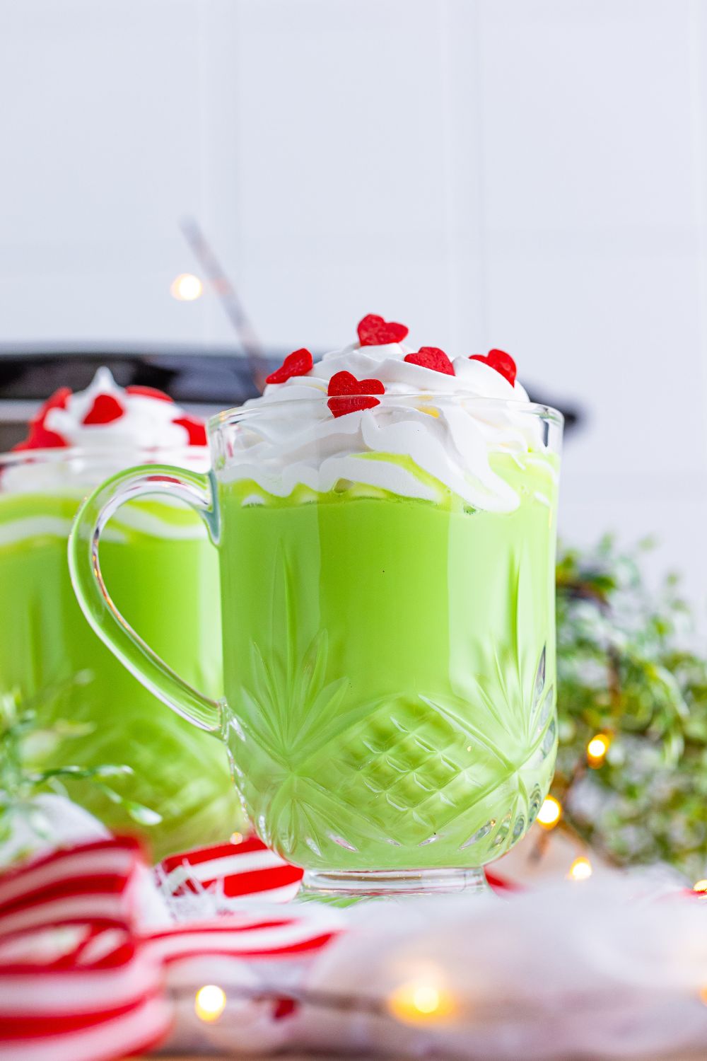 glasses of green hot chocolate on table with whipped cream and red candies on top