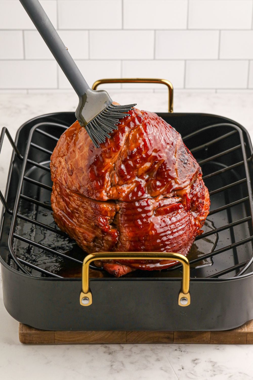 brushing ham with a glaze on roasting pan