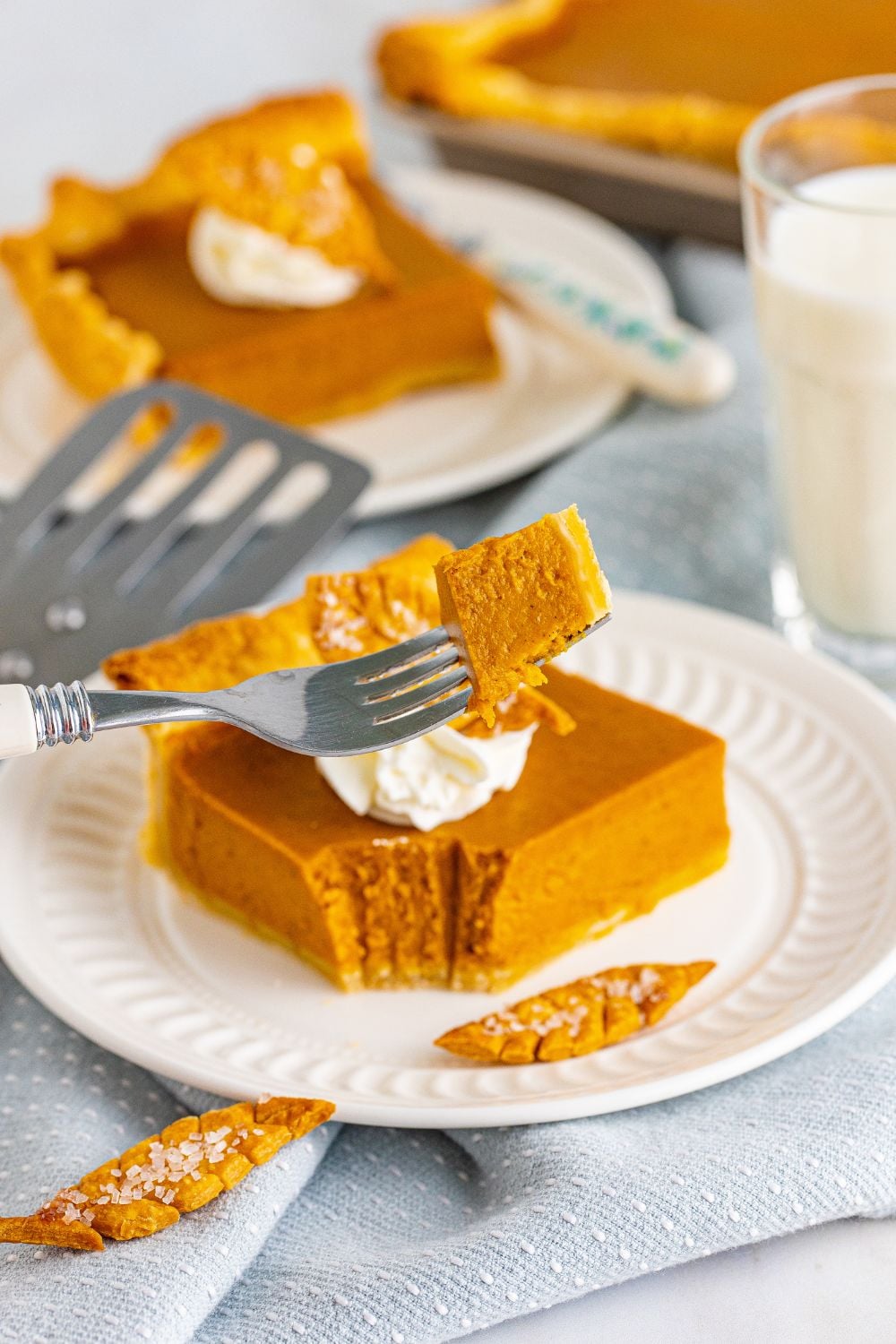slice of pumpkin pie on plate with bite on a fork