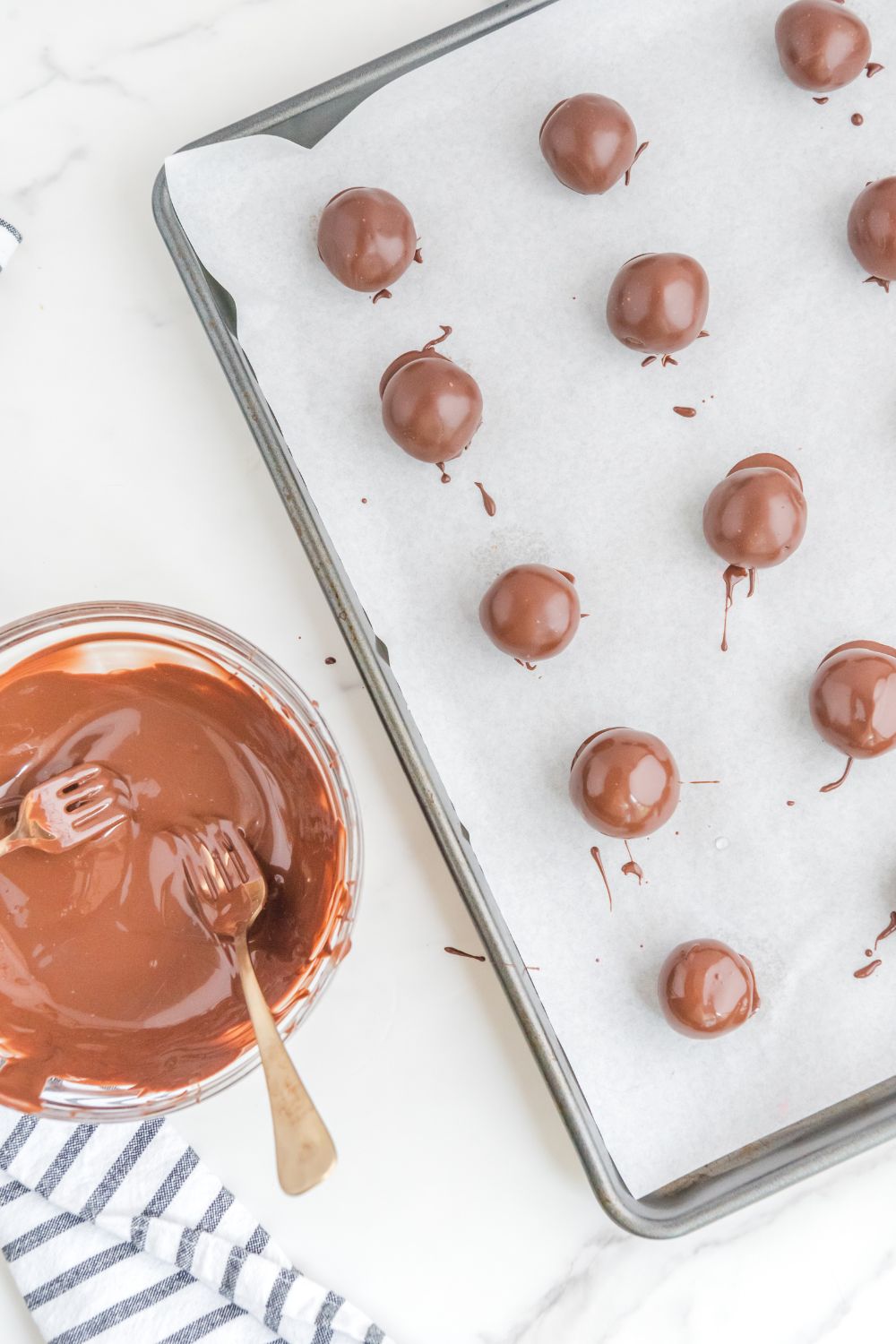 brownie bites dipped in chocolate on a baking sheet