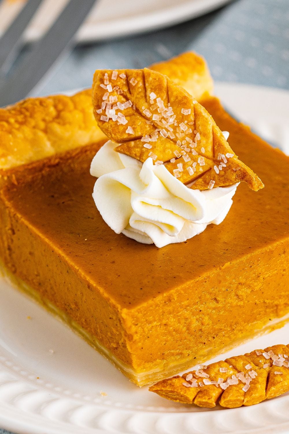 slice of pumpkin pie with cool whip and leaf crust on top