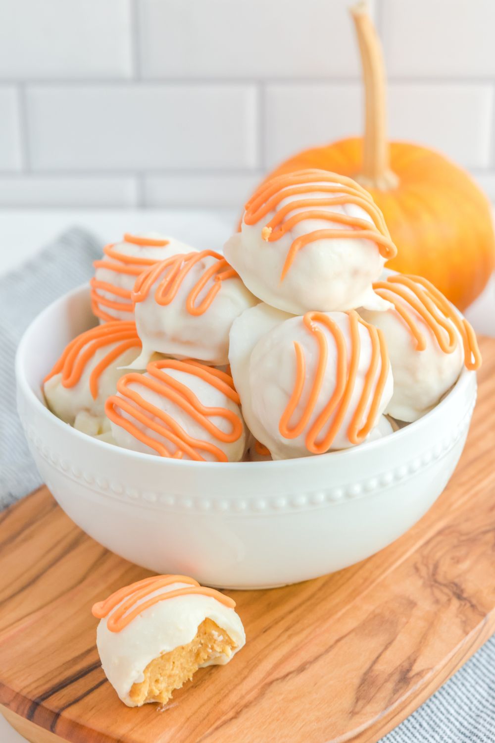 White Chocolate Pumpkin Truffles on a bowl with one sitting outside of bowl with bite taken out of it 