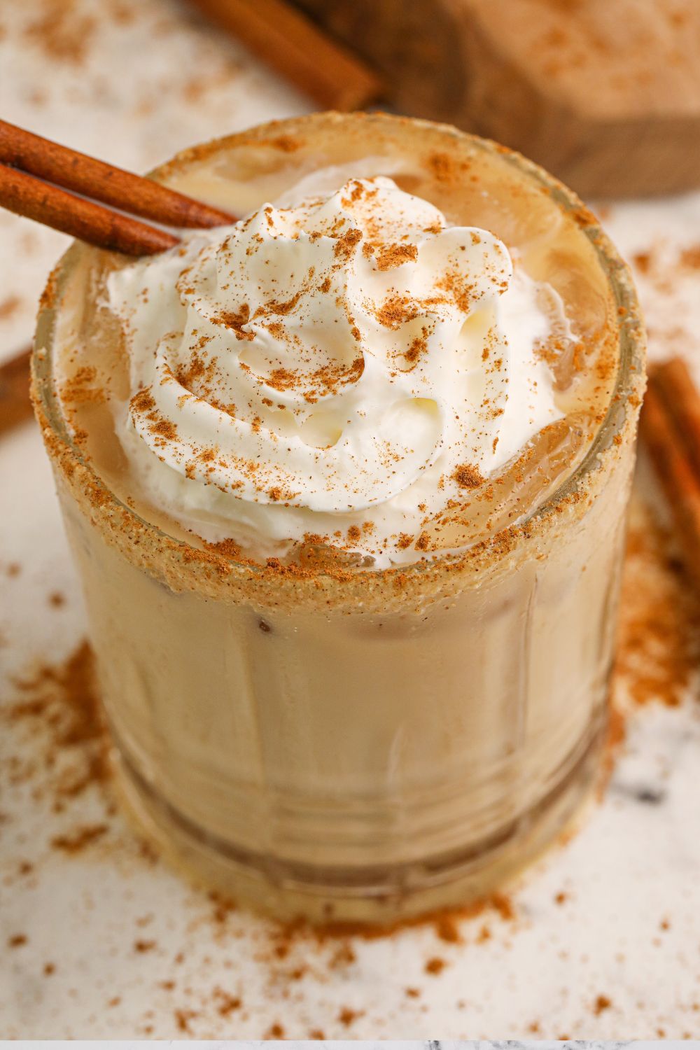 pumpkin pie white russian in a glas on table with pumpkin spice seasoning on table around it