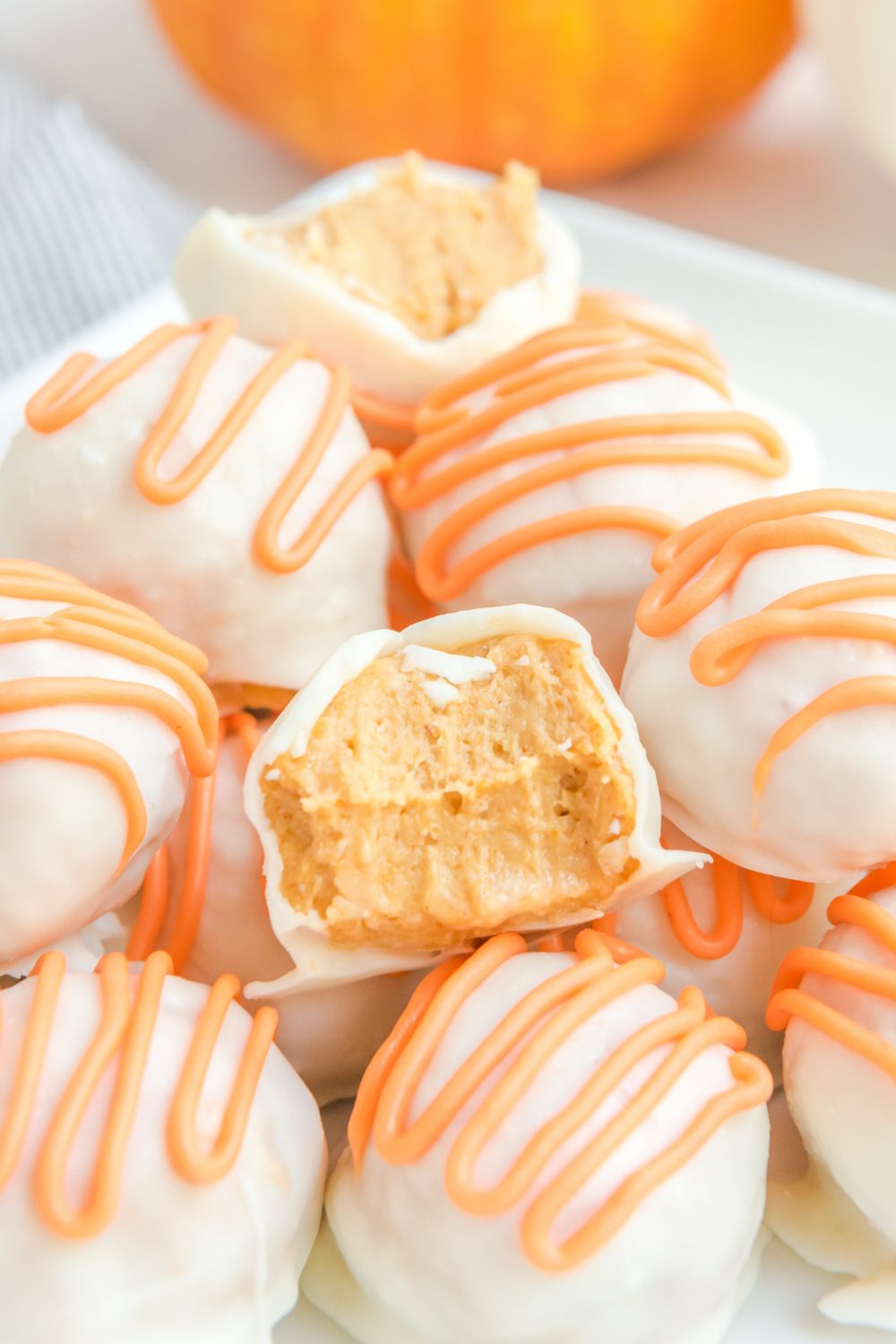 White Chocolate Pumpkin Truffles on plate with a few that have bites taken out of them 