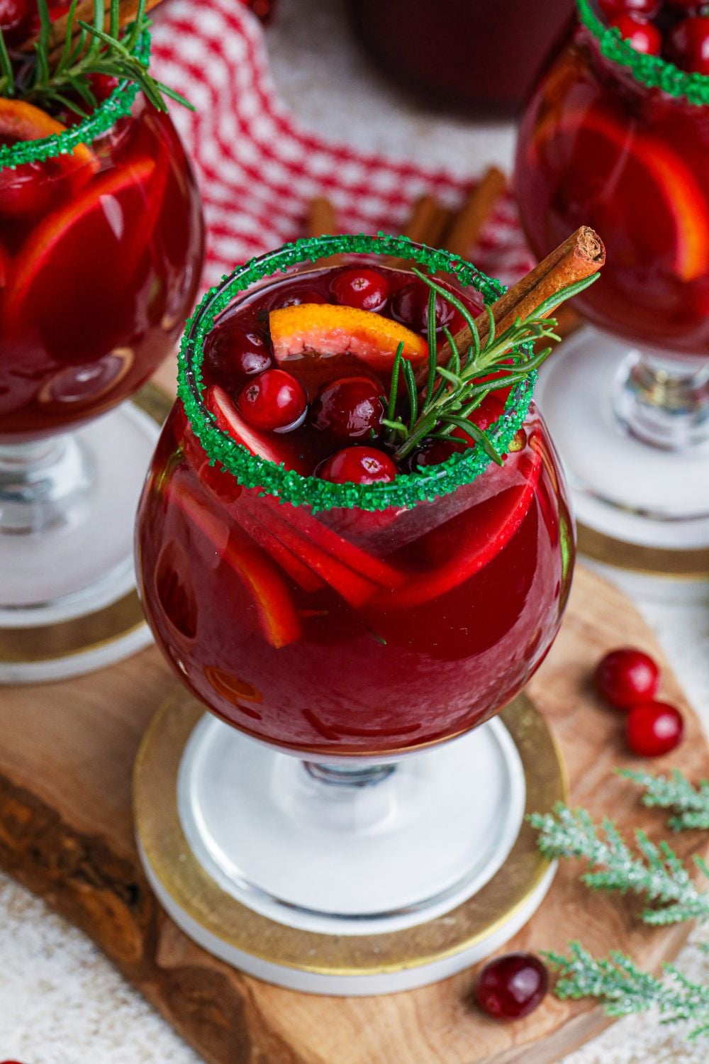 red wine cocktail with fruit on table with berries and herbs around it on table