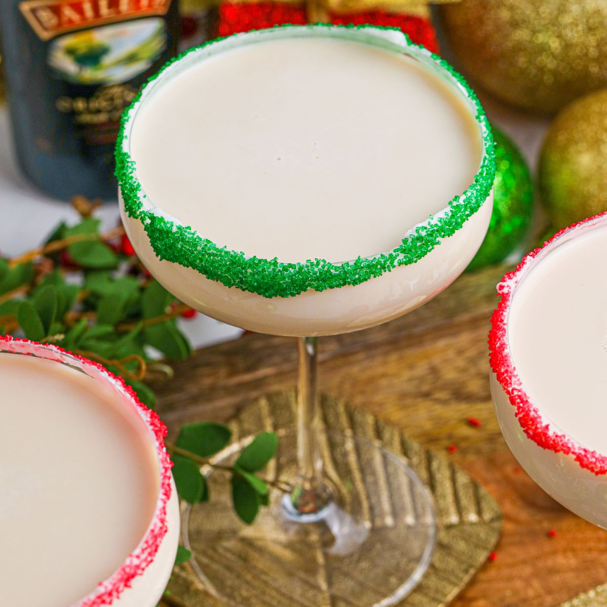 Sugar Cookie Cocktails in glasses with red and green sugar rims on a wooden table 