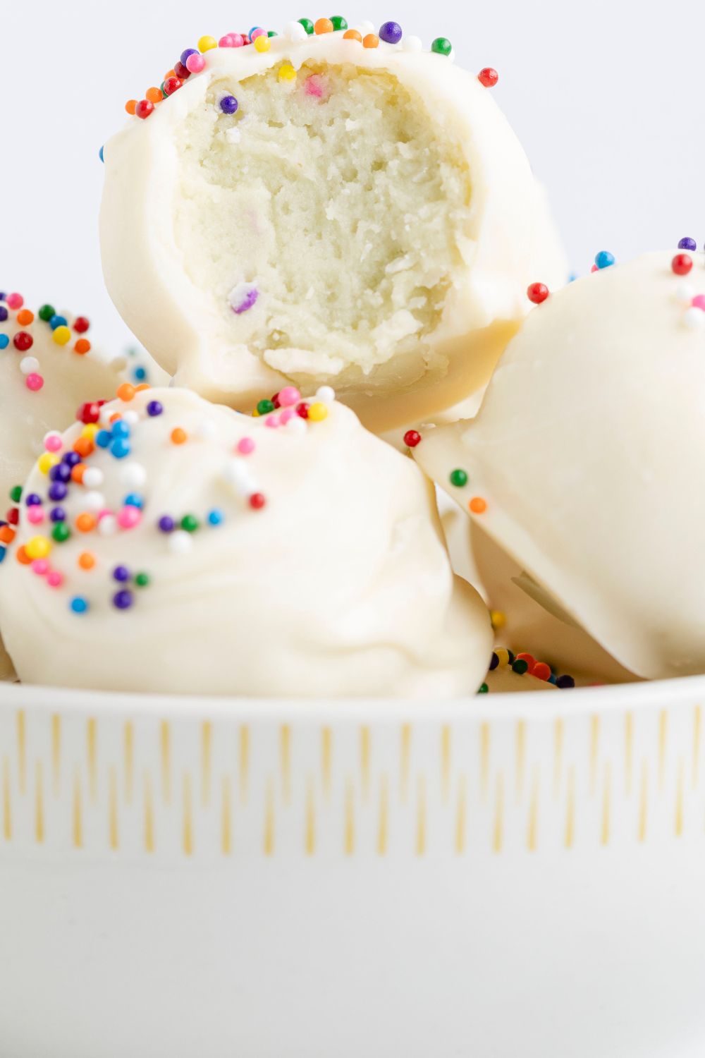 Sugar Cookie Truffles in a white bowl with a bite taken out of it 