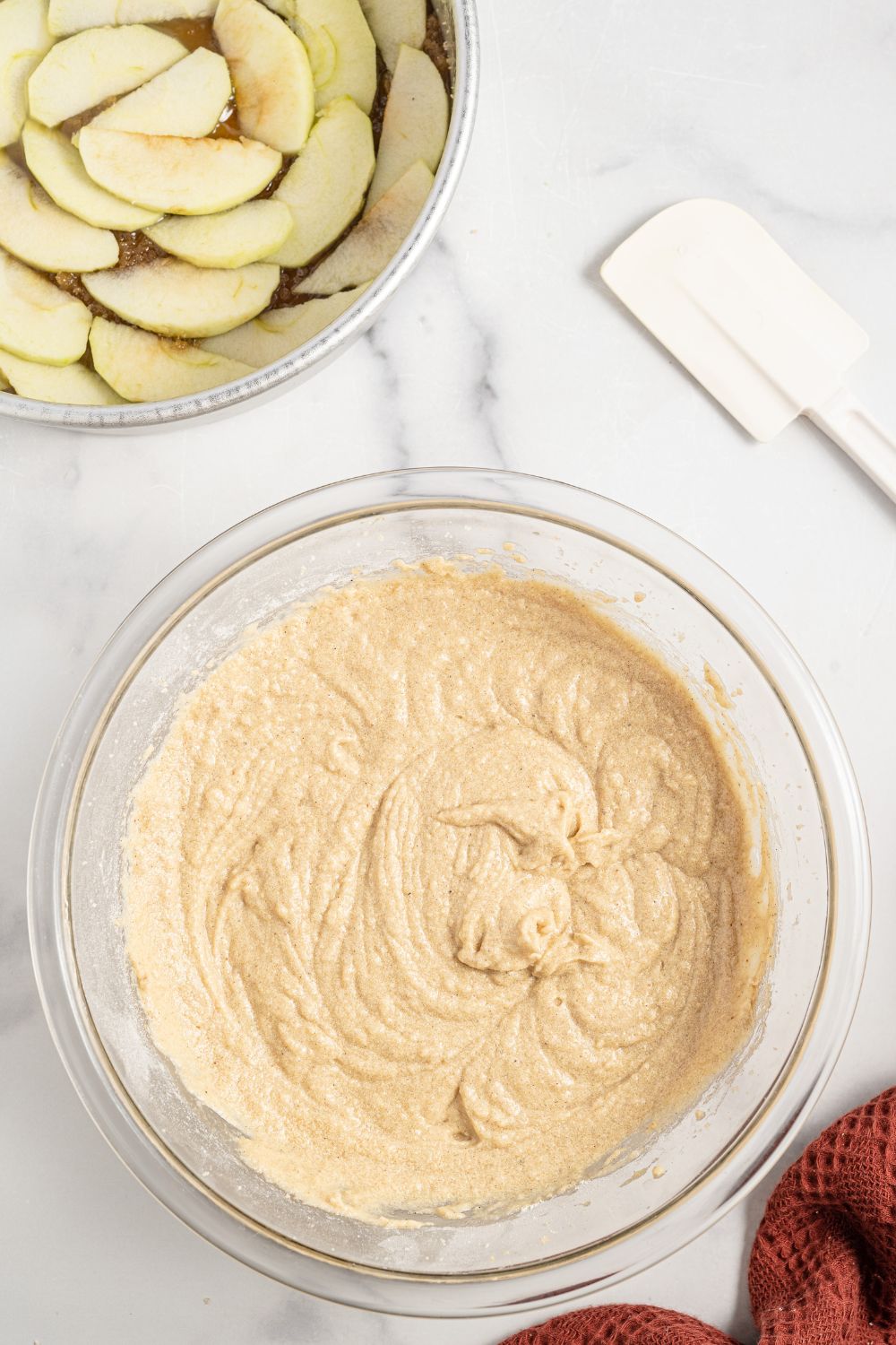 bowl with cake batter and a pan with sliced apples in pan
