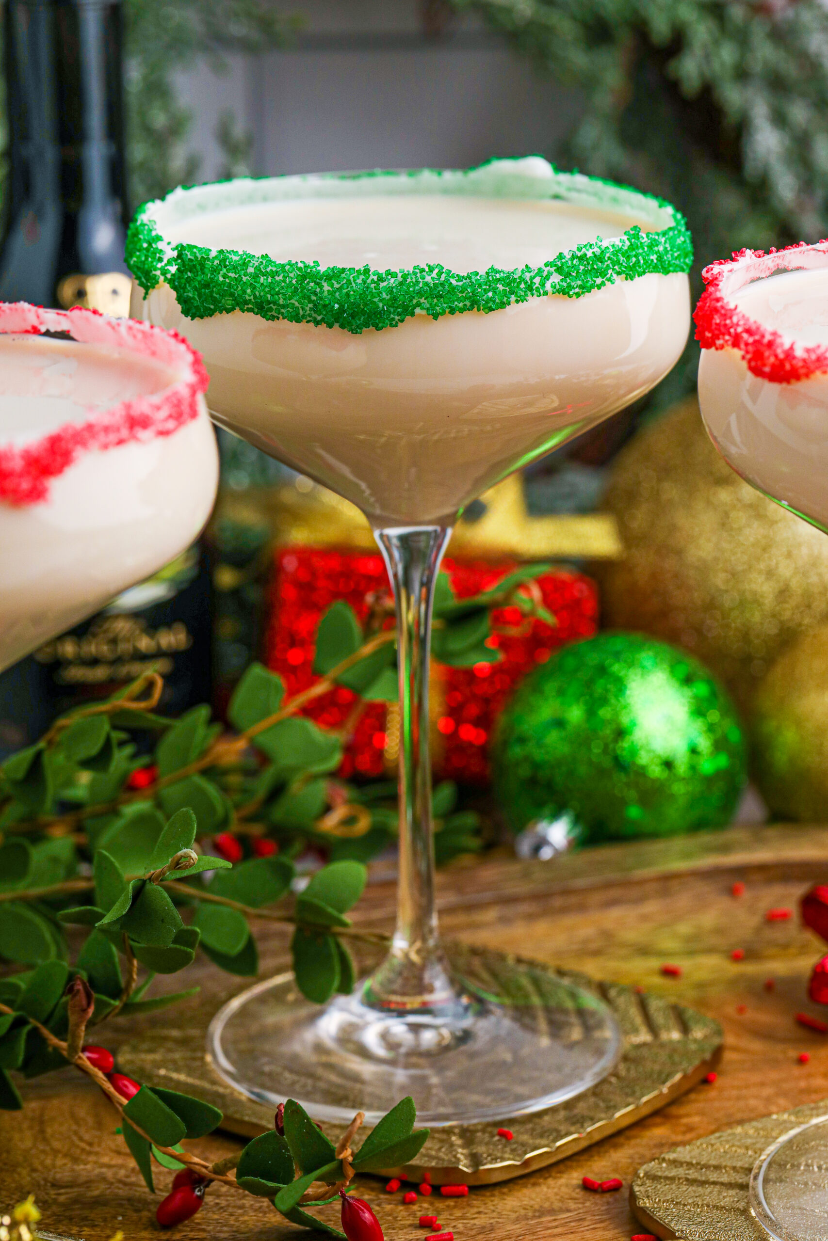 Sugar Cookie Cocktails in glasses with red and green sugar rims on a wooden table 