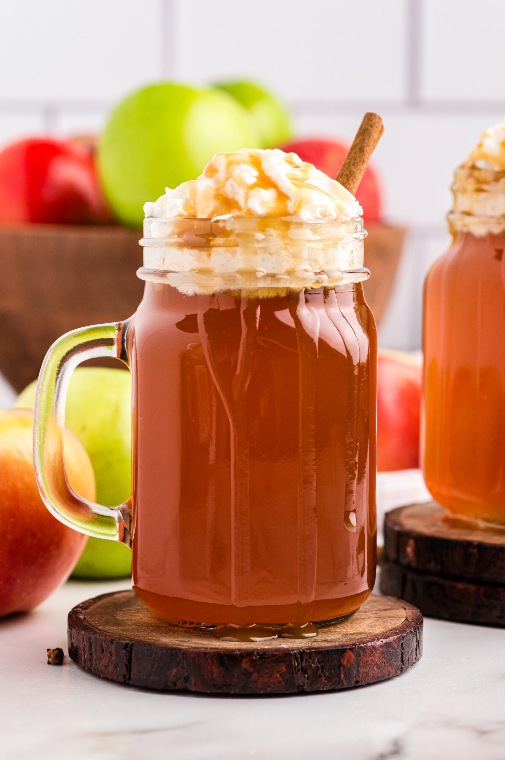 Crock Pot Caramel Apple Cider in a mason jar with whipped cream and syrup drizzled on top