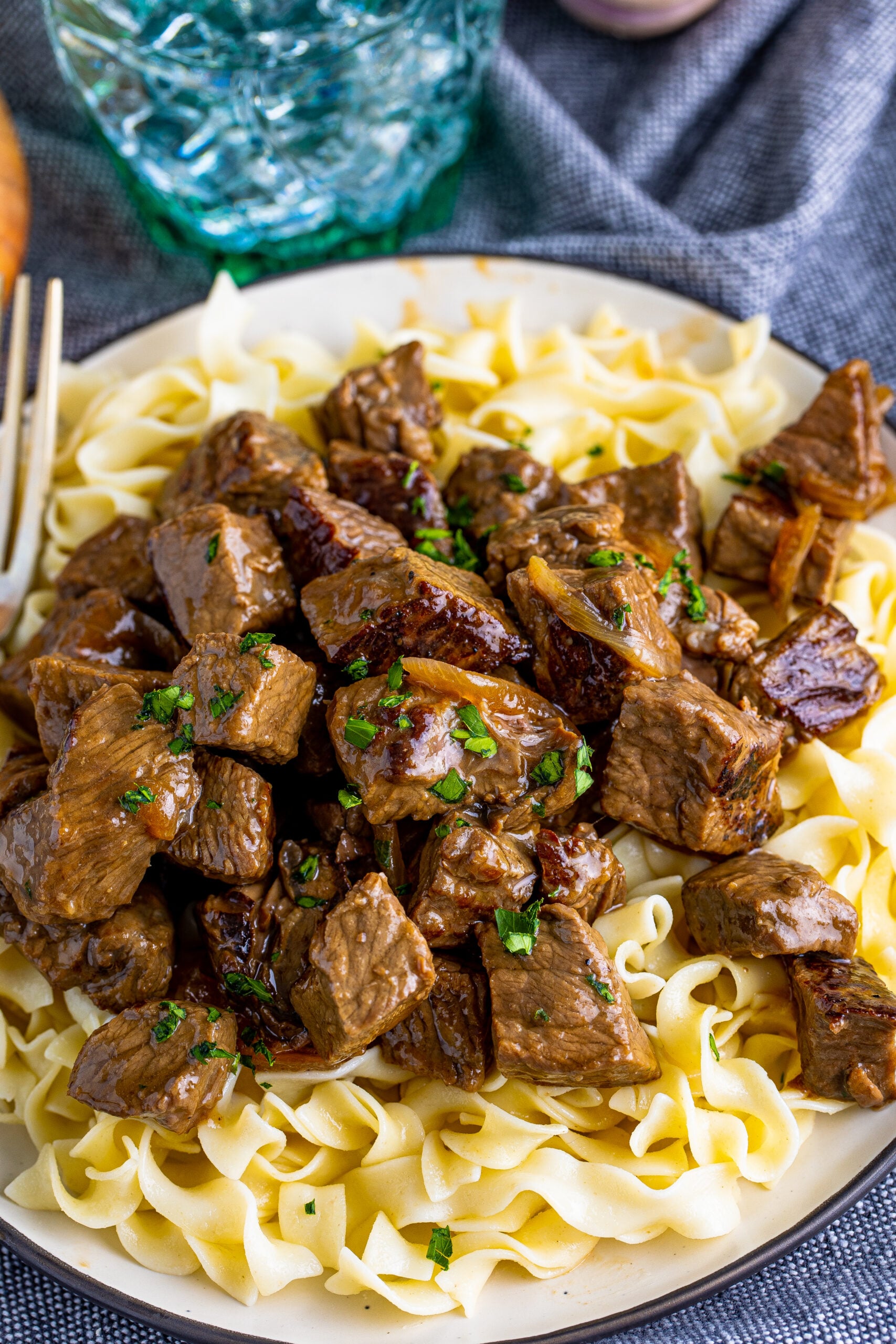 steak bites served over a bed of noodles on a plate