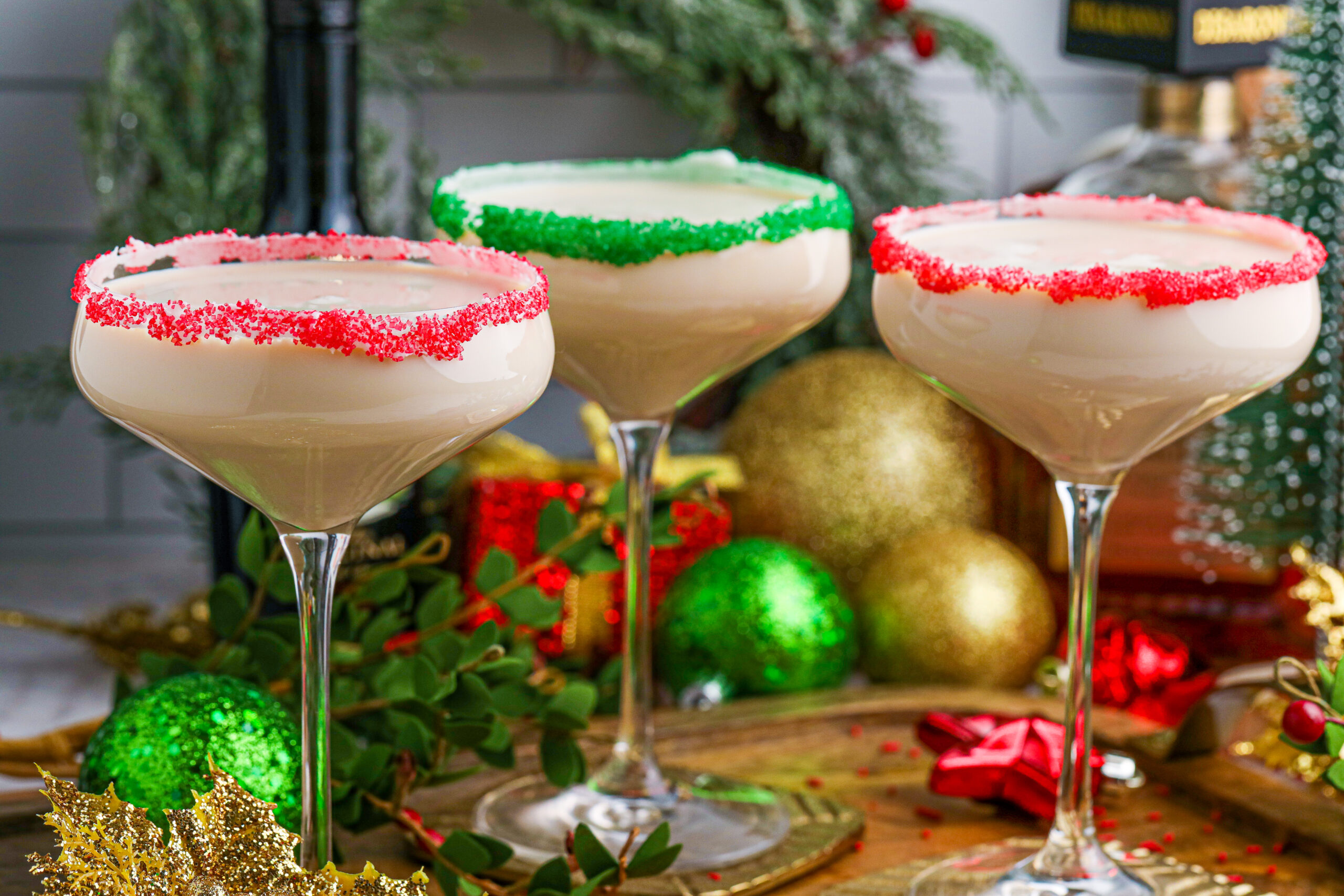 Sugar Cookie Cocktails in glasses with red and green sugar rims on a wooden table 