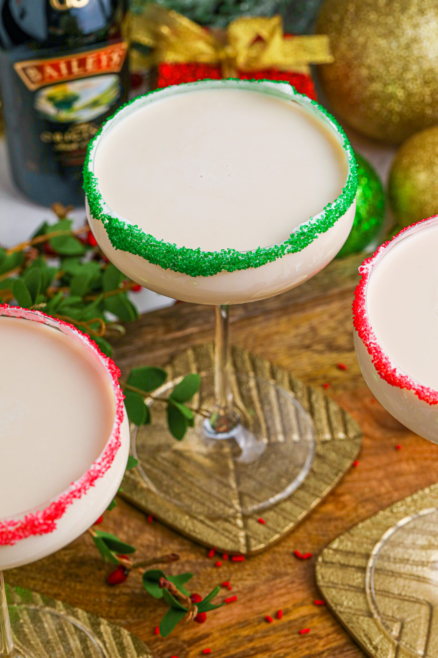 Sugar Cookie Cocktails in glasses with red and green sugar rims on a wooden table 