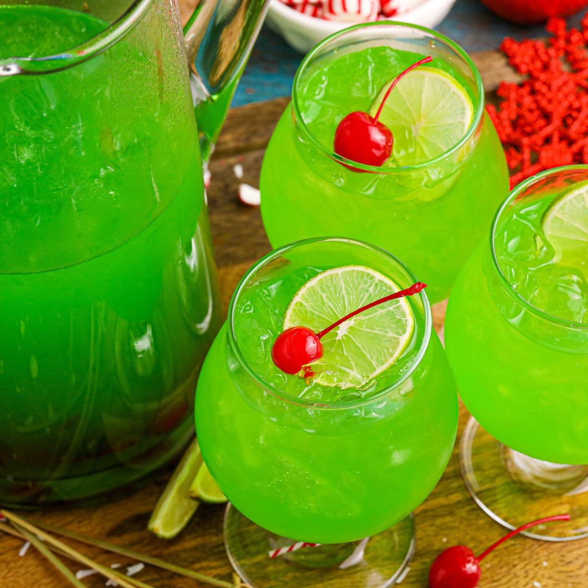Grinch Punch in a clear glass on a table with a cherry and a lime slice in the glasses