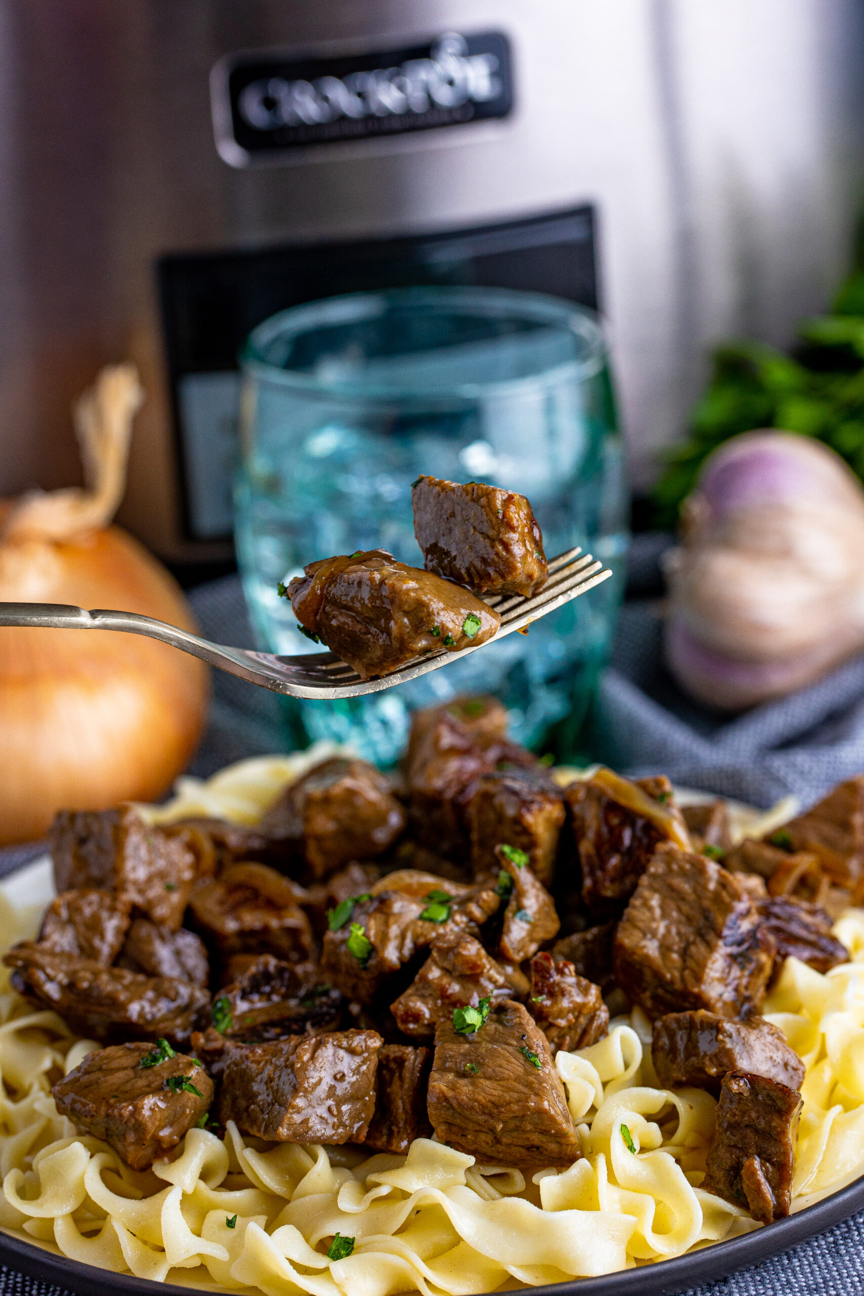 fork with steak bites on it and a crockpot behind it in image