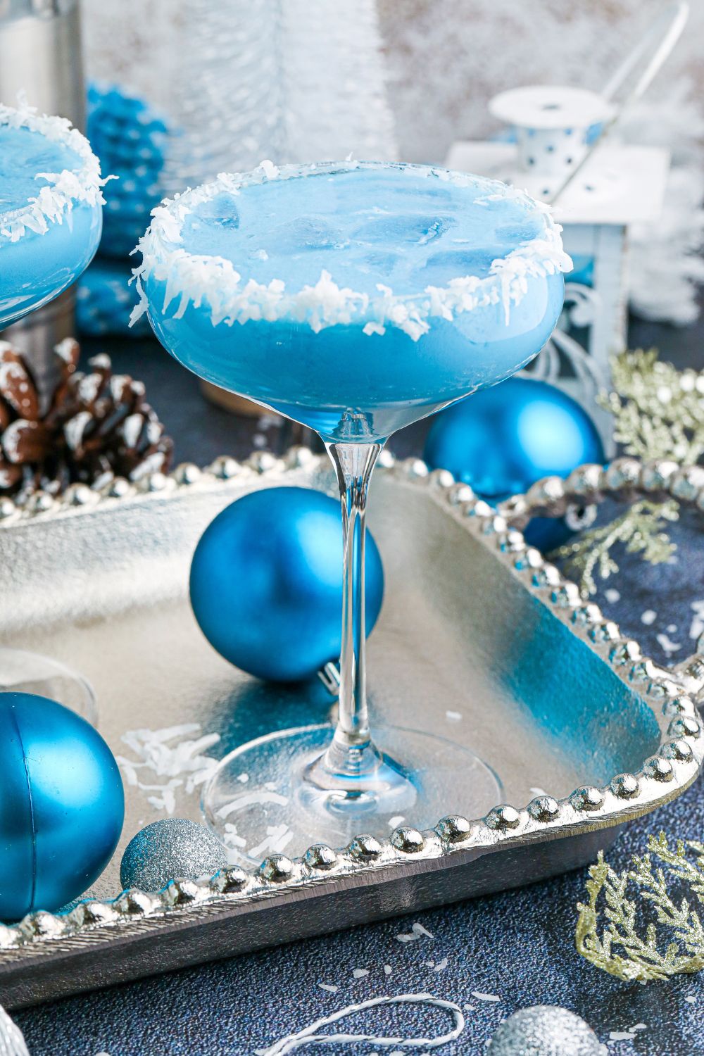 Blue Christmas Cocktail on table with blue Christmas ornaments around it 
