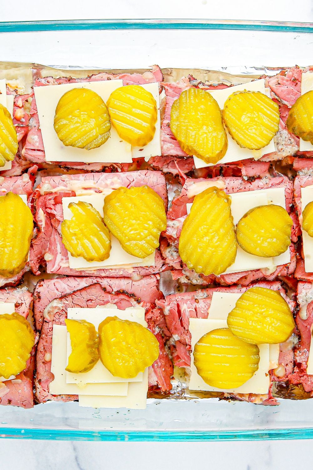sliders with meat, cheese and pickles on top