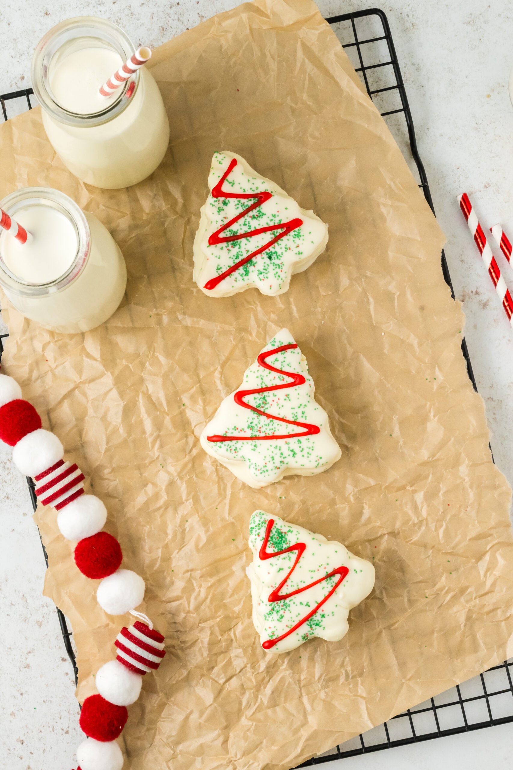 little debbie cakes on a parchment paper tray with glasses of milk around it