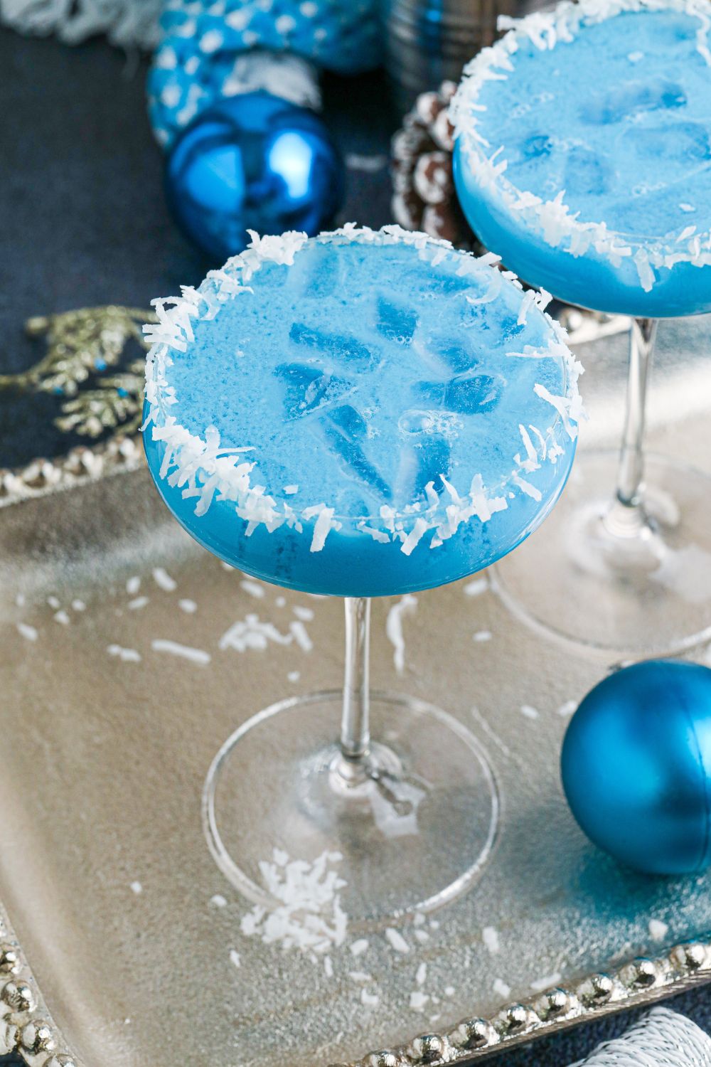 Christmas cocktails on silver platter with blue Christmas balls around it 