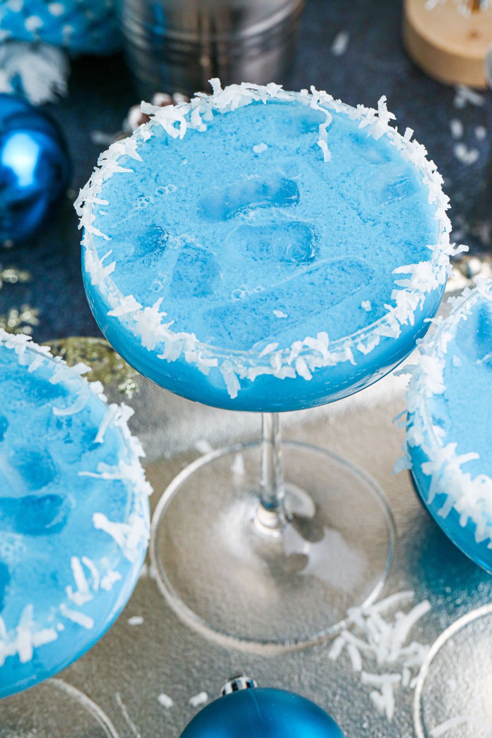 blue colored cocktails in glass with coconut flakes around the rim 