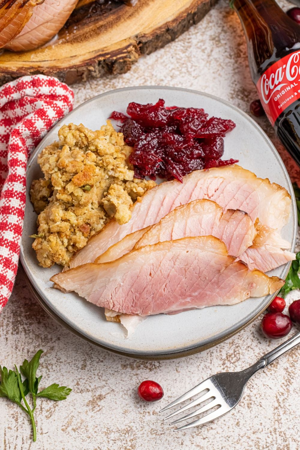 plate and fork with a ham dinner on table with bottle of coca cola on side
