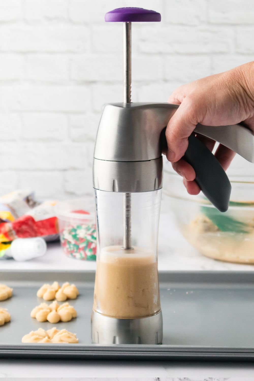 holding cookie press above cookie sheet