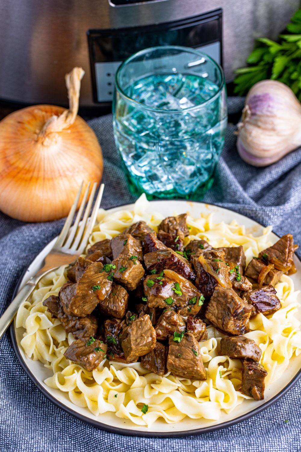 plate with fork on side showing plate of egg noodles with steak bites on top of noodles