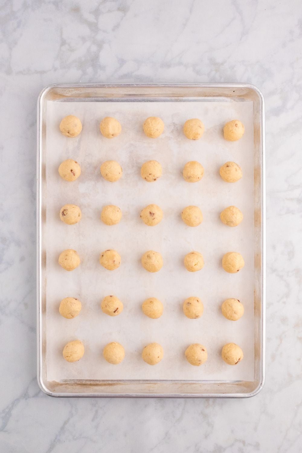 raw cookie balls on a baking sheet on table