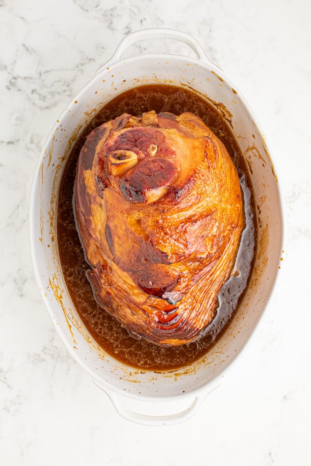 cooked ham with glaze in bottom of pan