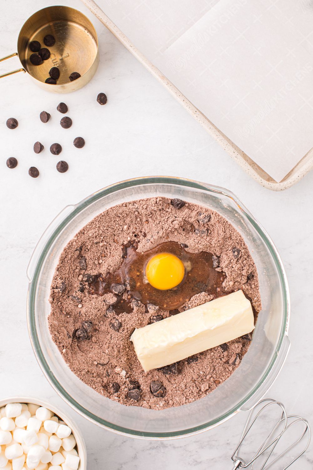 cookie mix in a bowl with mini chocolate chips on table around it