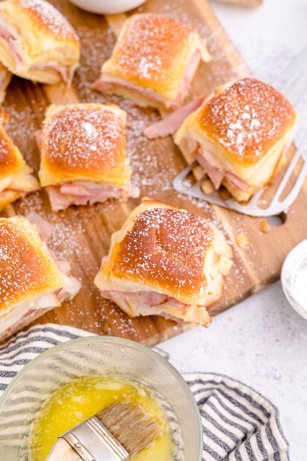 sliders placed on a cutting board with ingredients around it on table