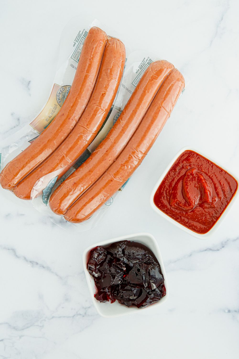 kielbasa on table with chili sauce and grape jelly in bowls besides it