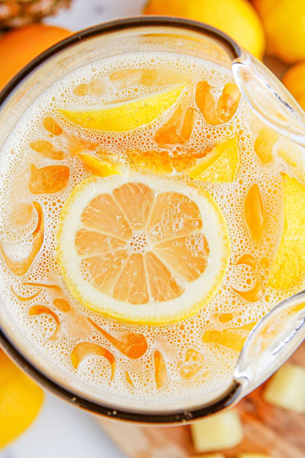 overhead look of party punch in a glass pitcher on table garnishes with sliced fruit