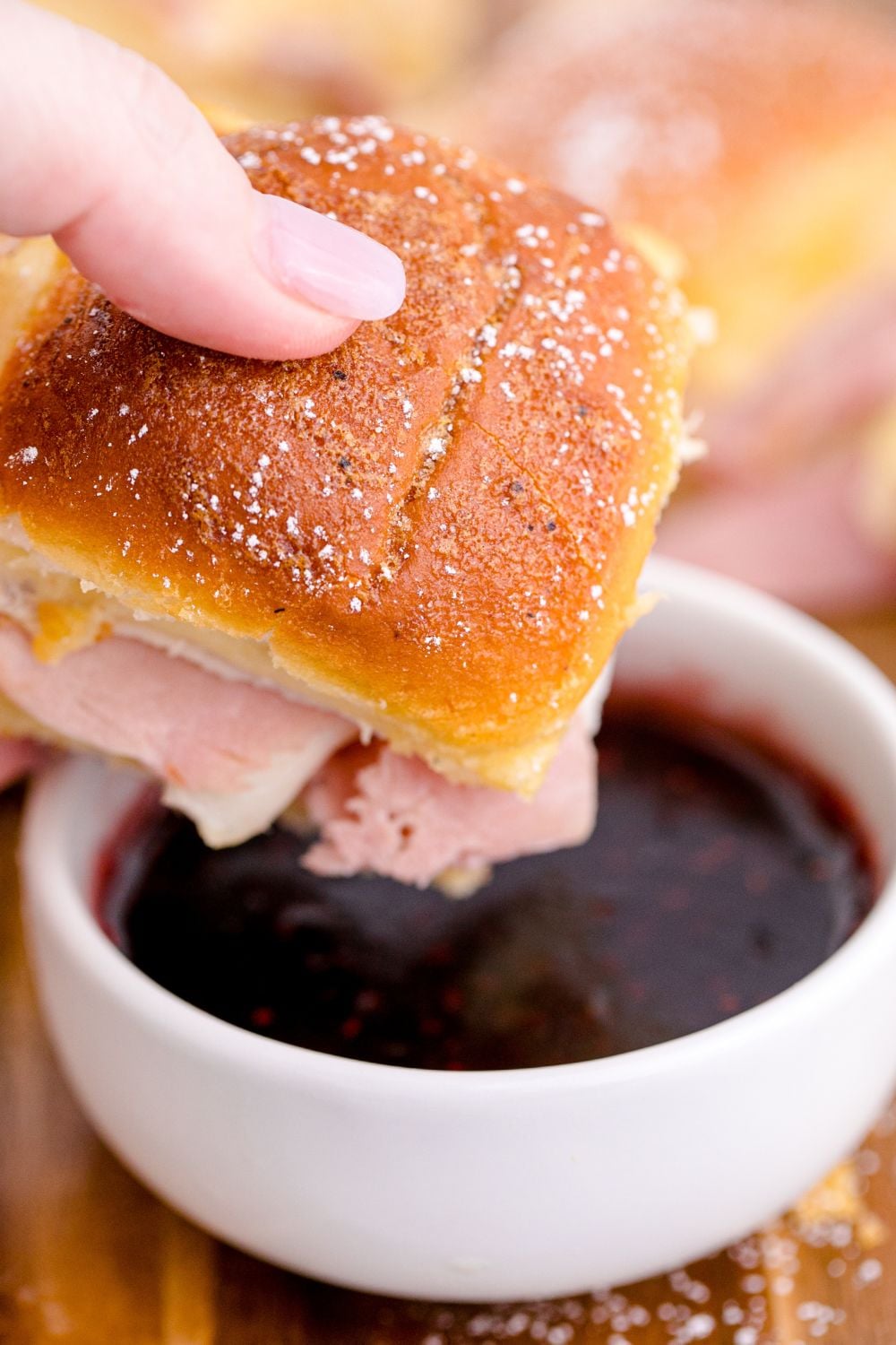 slider about to dip in a jam preserve sauce in a white bowl