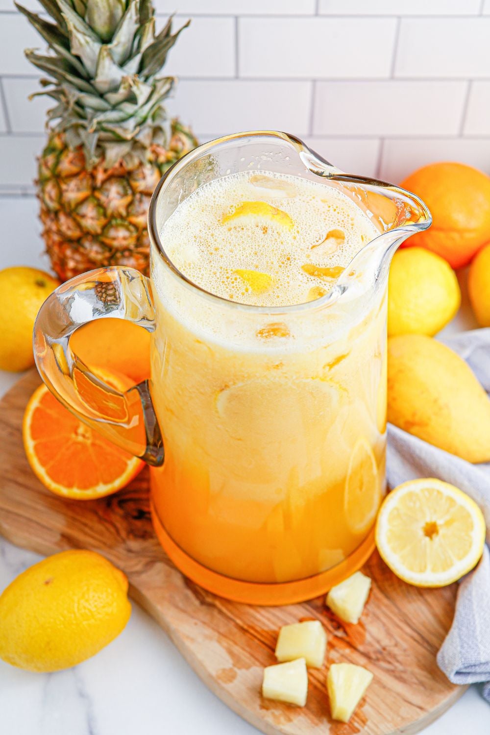 party punch in a glass pitcher sitting on table with fruit all around it