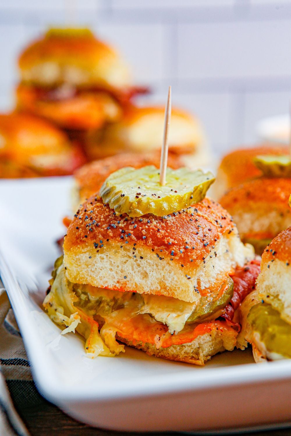 seasoned bun laded with cheese and pastrami and topped with a pickle and toothpick