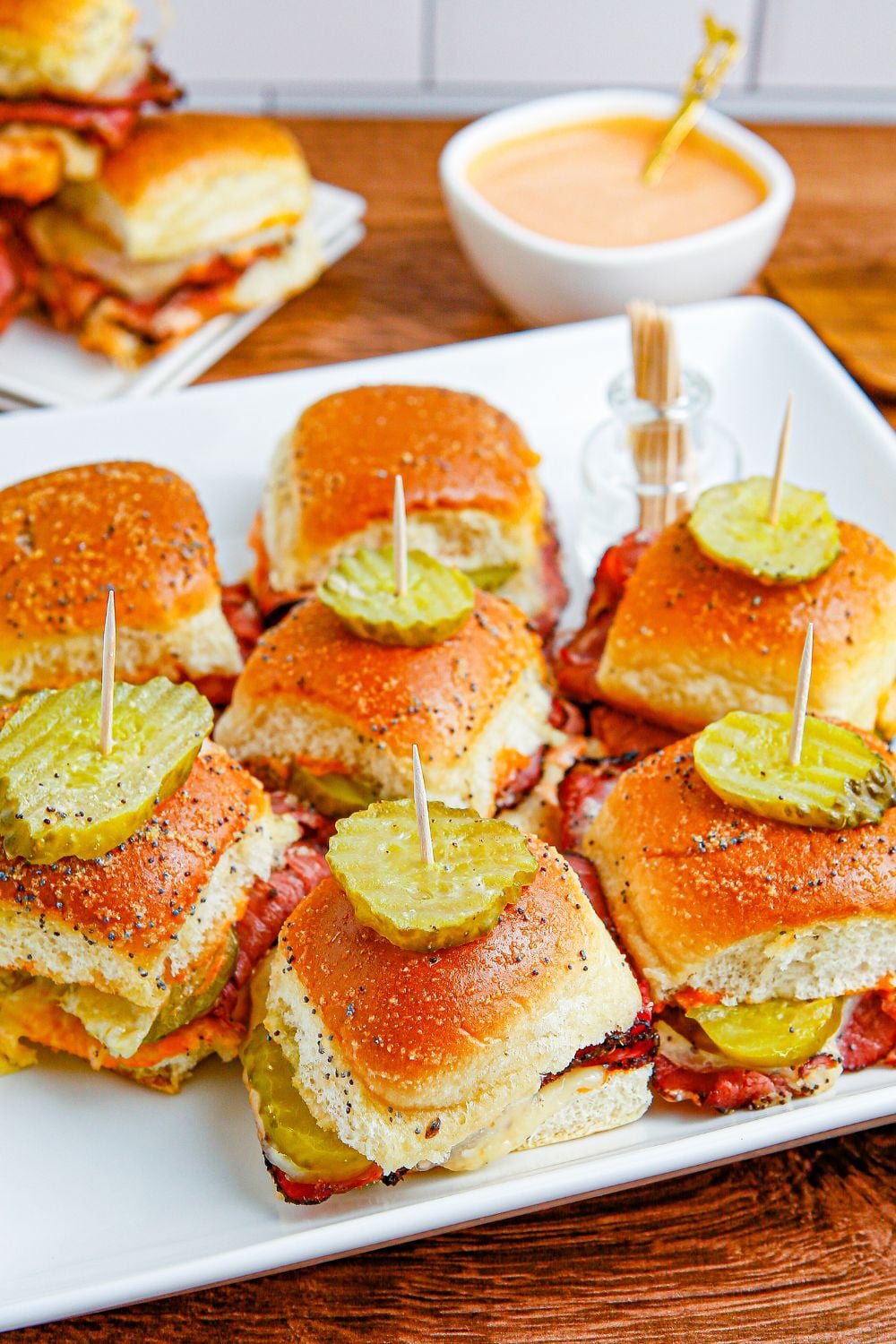 tray with a handful of sandwiches on and dip in a white bowl behind it
