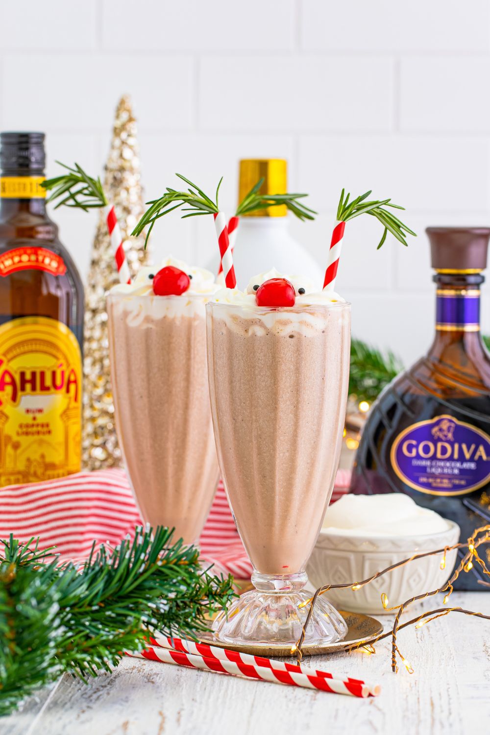tipsy milkshakes with alcohol bottles behind them on table