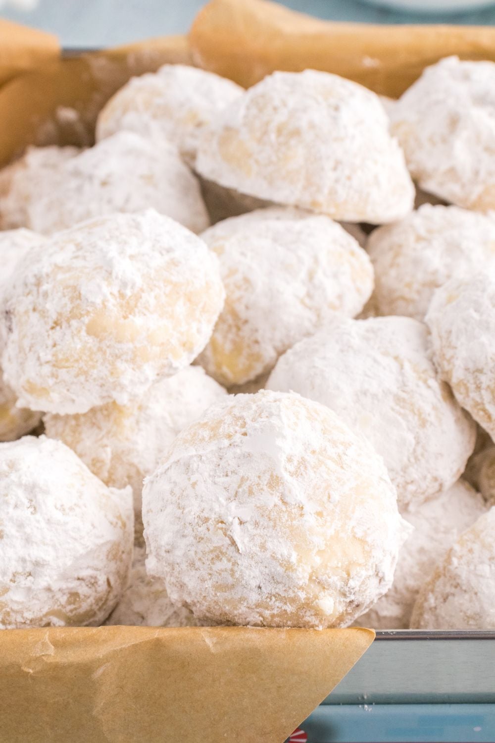 snow cookies in a tin with parchment paper in it
