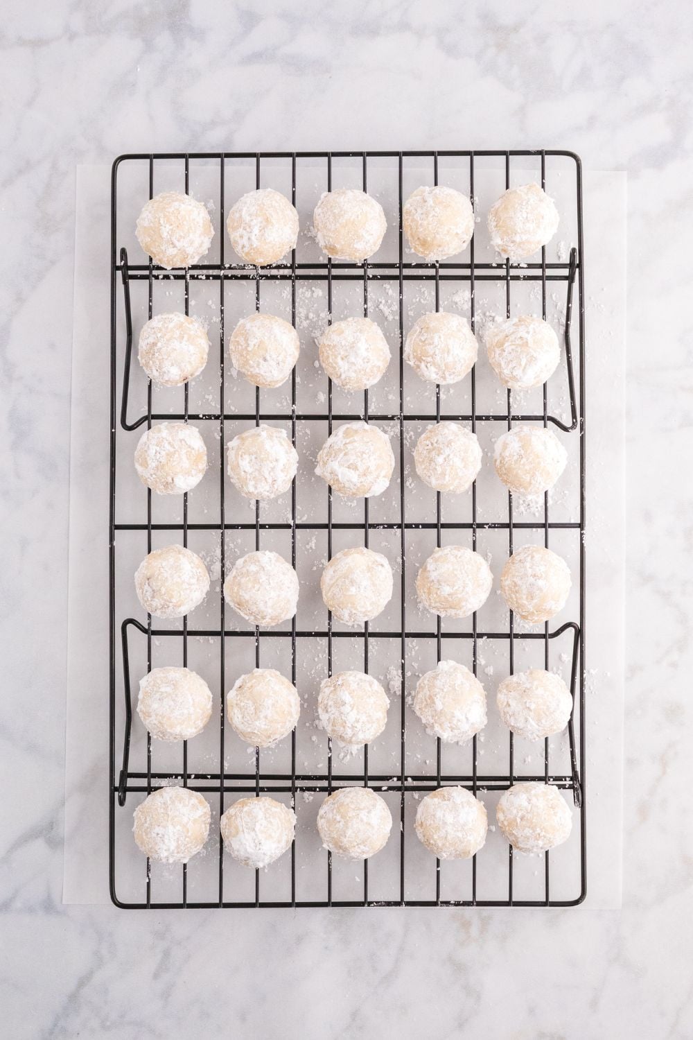 snowball cookies placed on a cooling rack on table