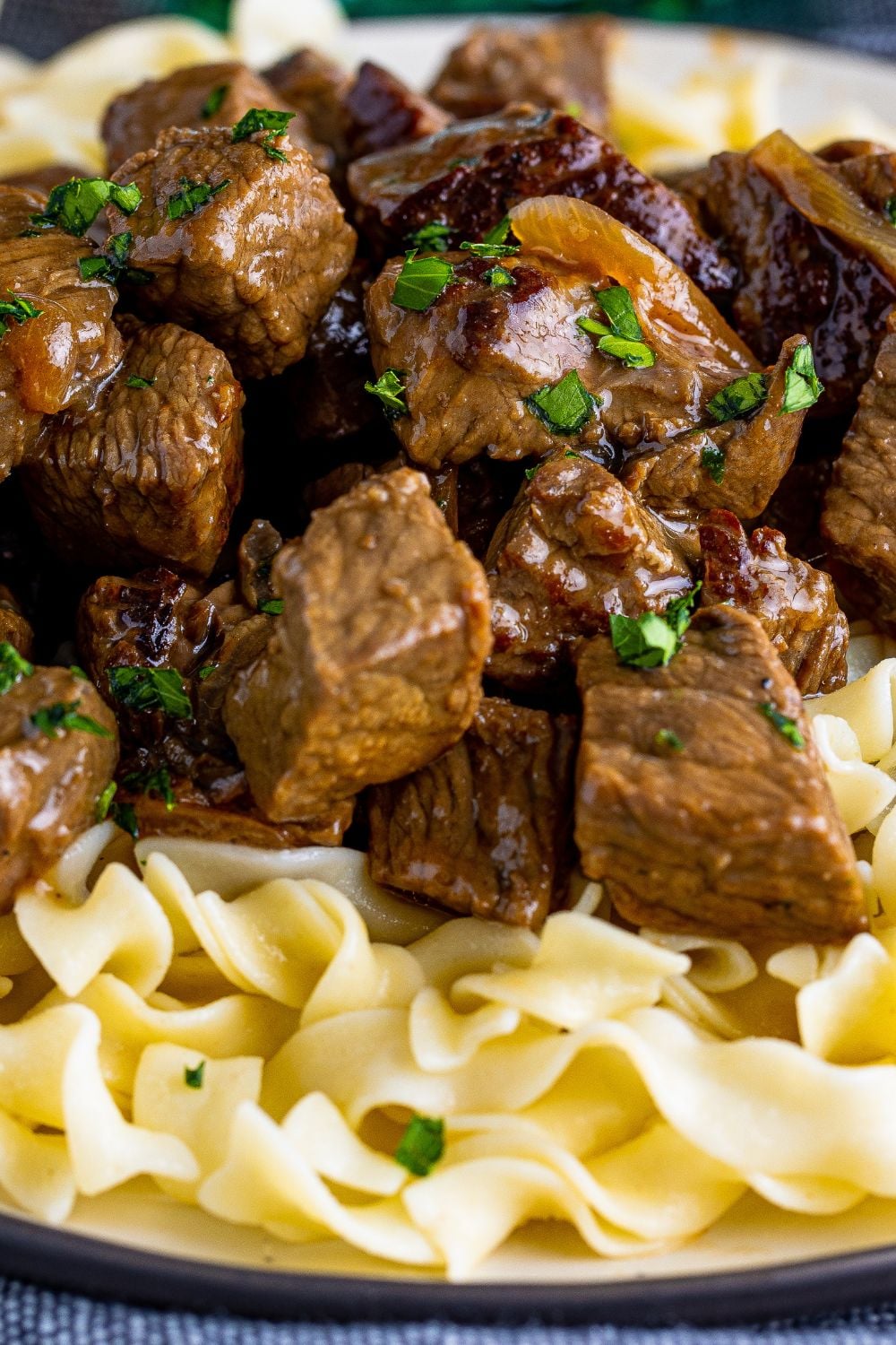 close up view of steak bites on plate with egg noodles under it