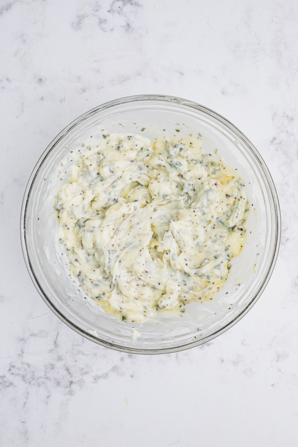 herb butter mixed together in a glass bowl on table